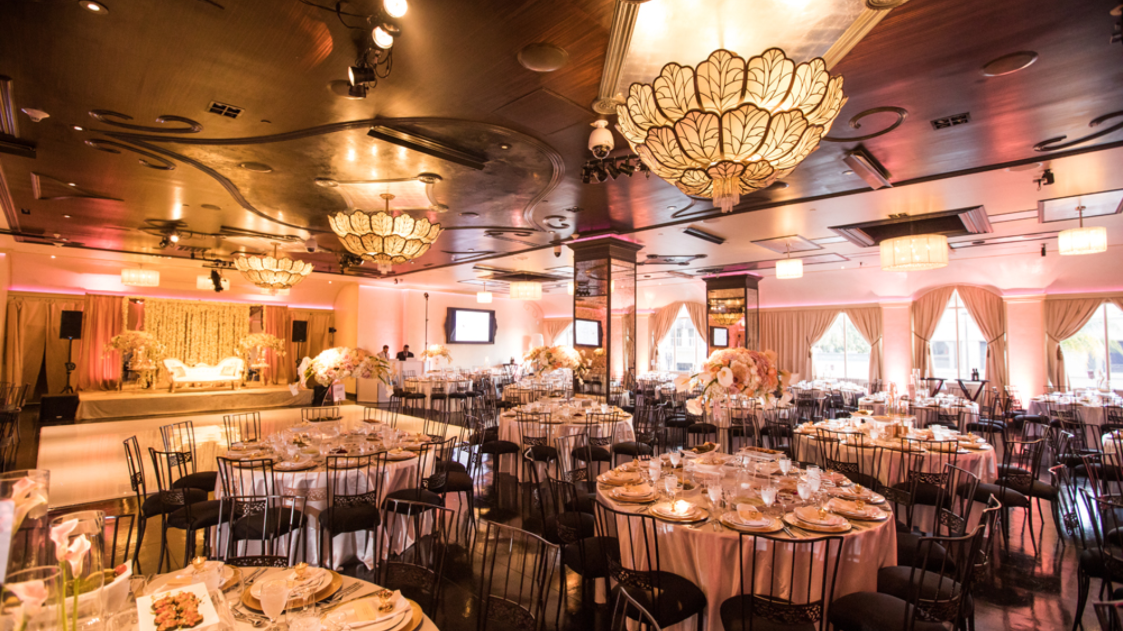 Noor Pasadena - Bronson Hospitality An elegant ballroom at Noor Pasadena featuring luxurious chandeliers, floral centerpieces, stylish table settings, and a sophisticated indoor reception atmosphere.