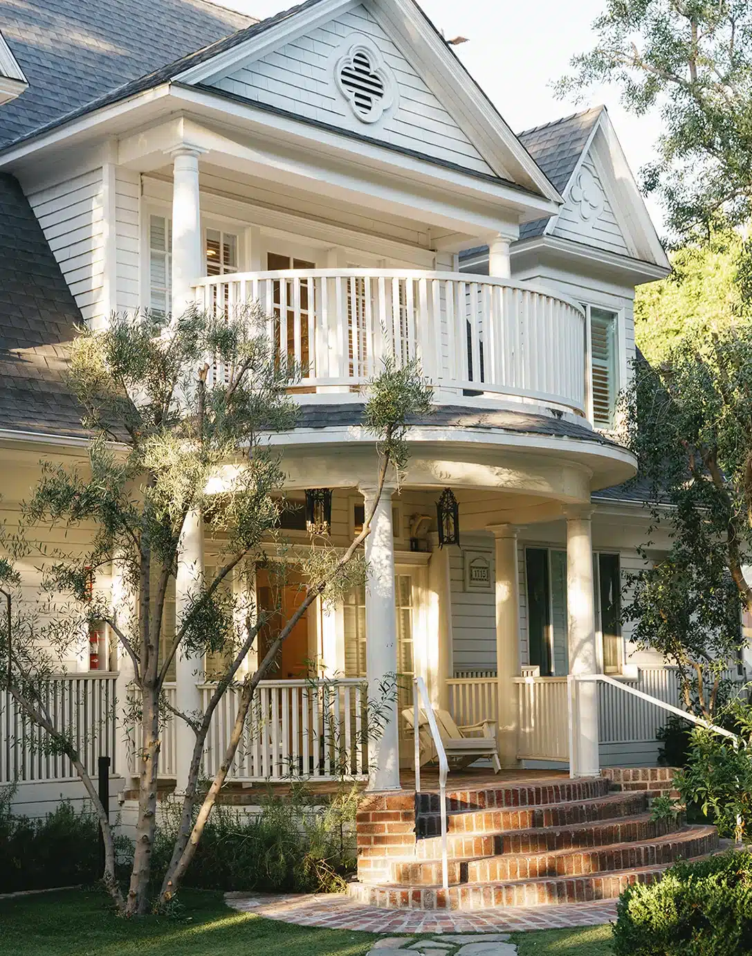 The restored Victorian farmhouse exterior featuring the signature curved balcony at Lombardi House.