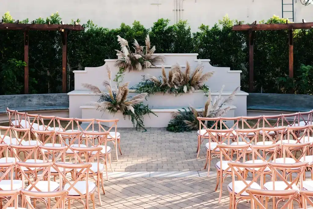Outdoor Casita Hollywood wedding ceremony setup with pampas grass and peach-colored chairs