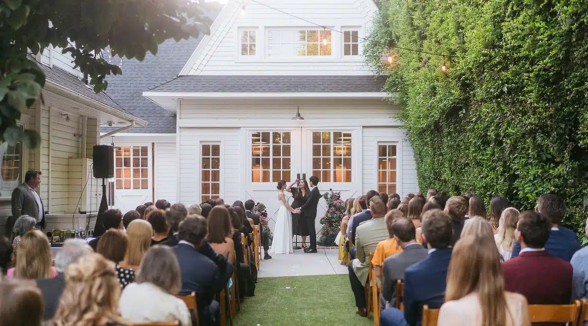 Outdoor wedding ceremony on the lawn in front of the white barn at Lombardi House.