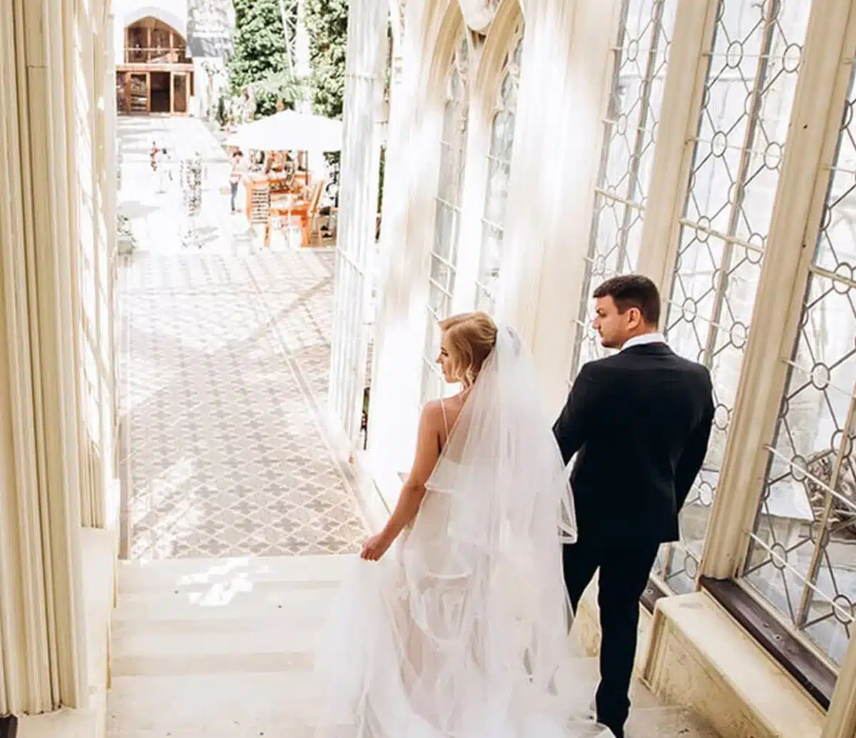 Bride and groom walking arm in arm through an elegant archway at Lombardi House, a Bronson Hospitality wedding and event venue