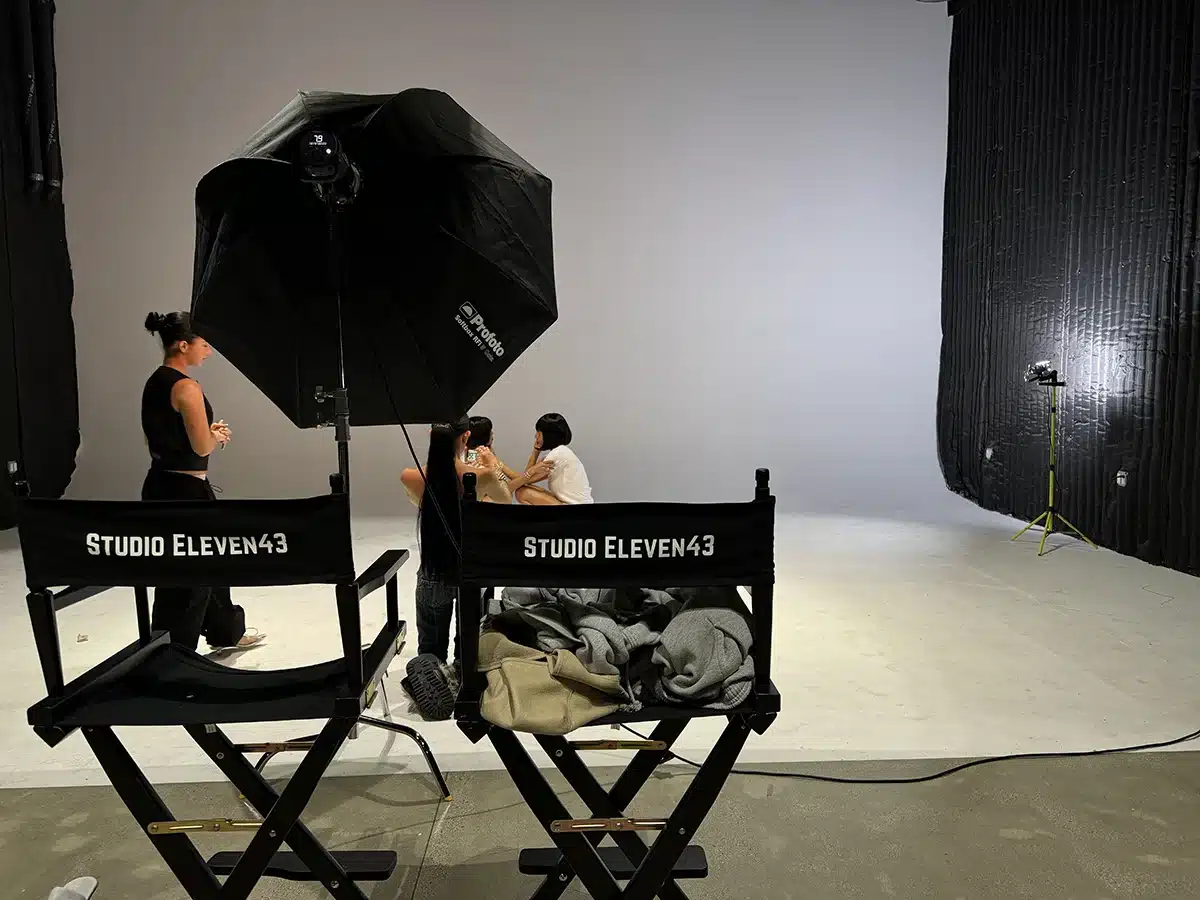 Photoshoot in progress at Studio Eleven43 with branded director chairs, softbox lighting, and crew on set in Los Angeles